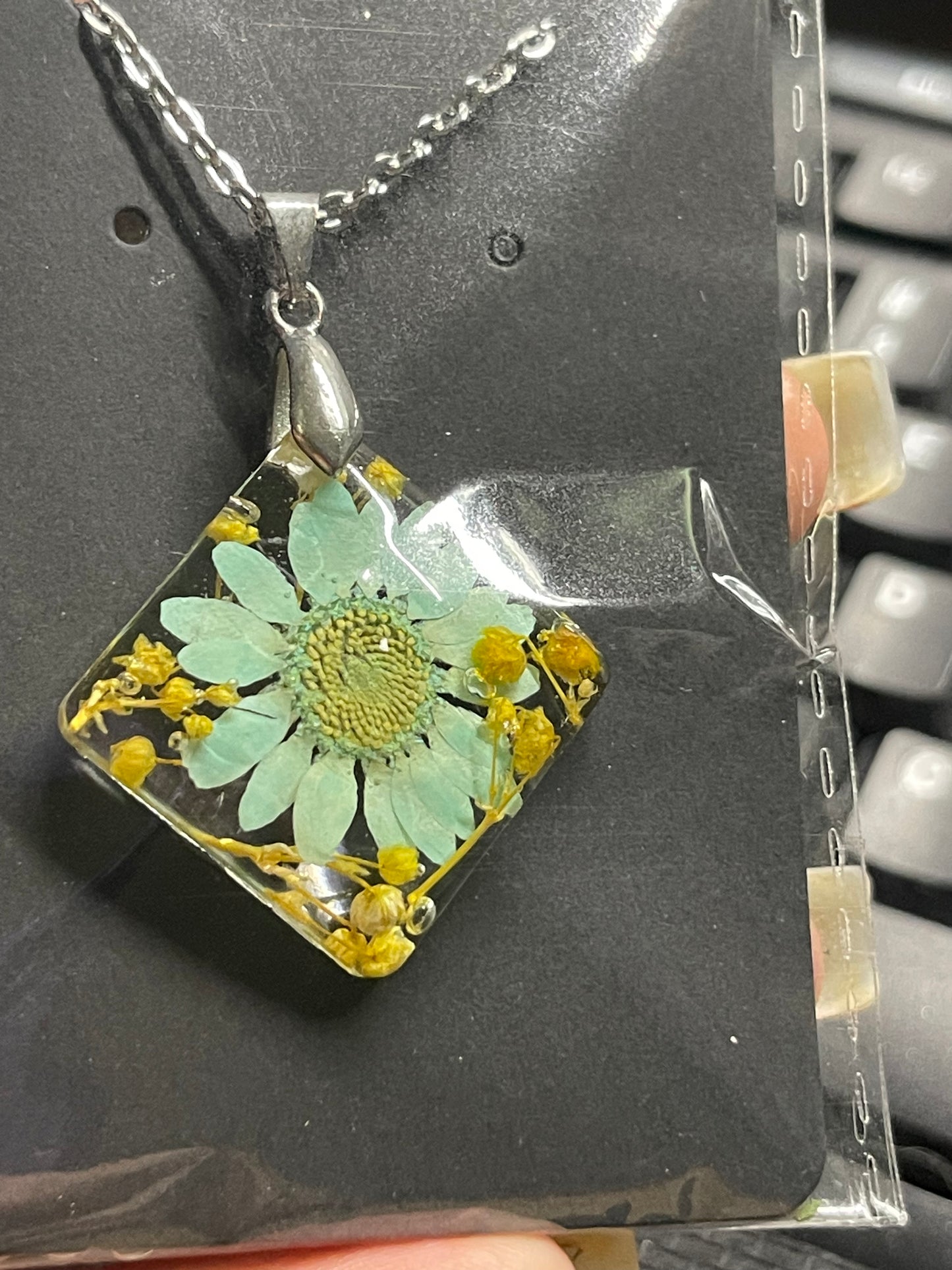 Teal daisy with baby’s breath preserved in resin on an 18” chain