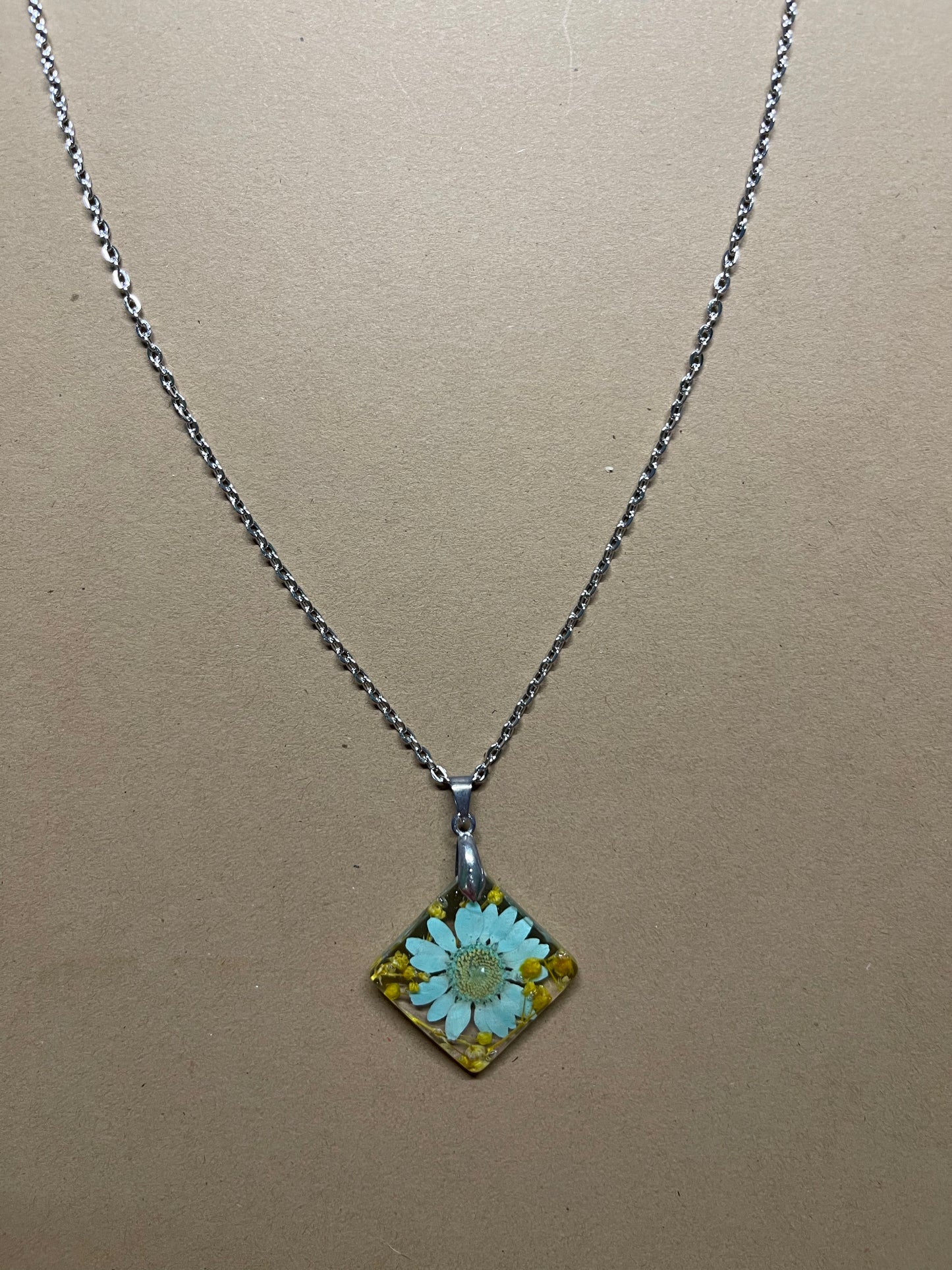 Teal daisy with baby’s breath preserved in resin on an 18” chain